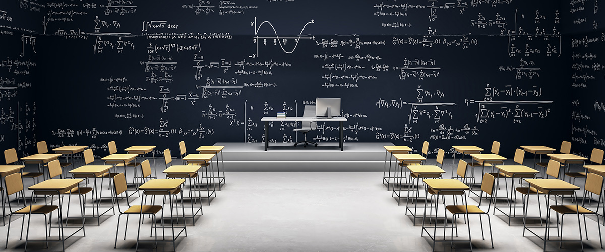 classroom with empty seats and desks and writing on a chalkboard
